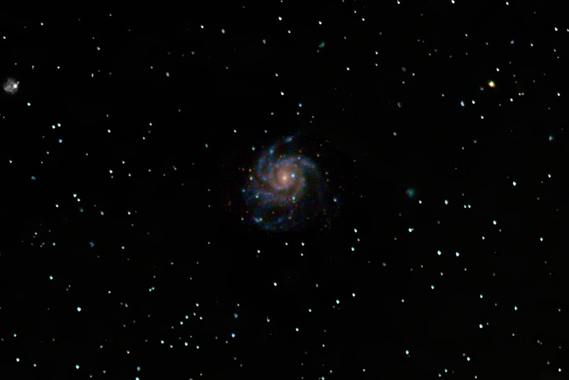 A dark sky shows a pinwheel galaxy and bright dots of stars.