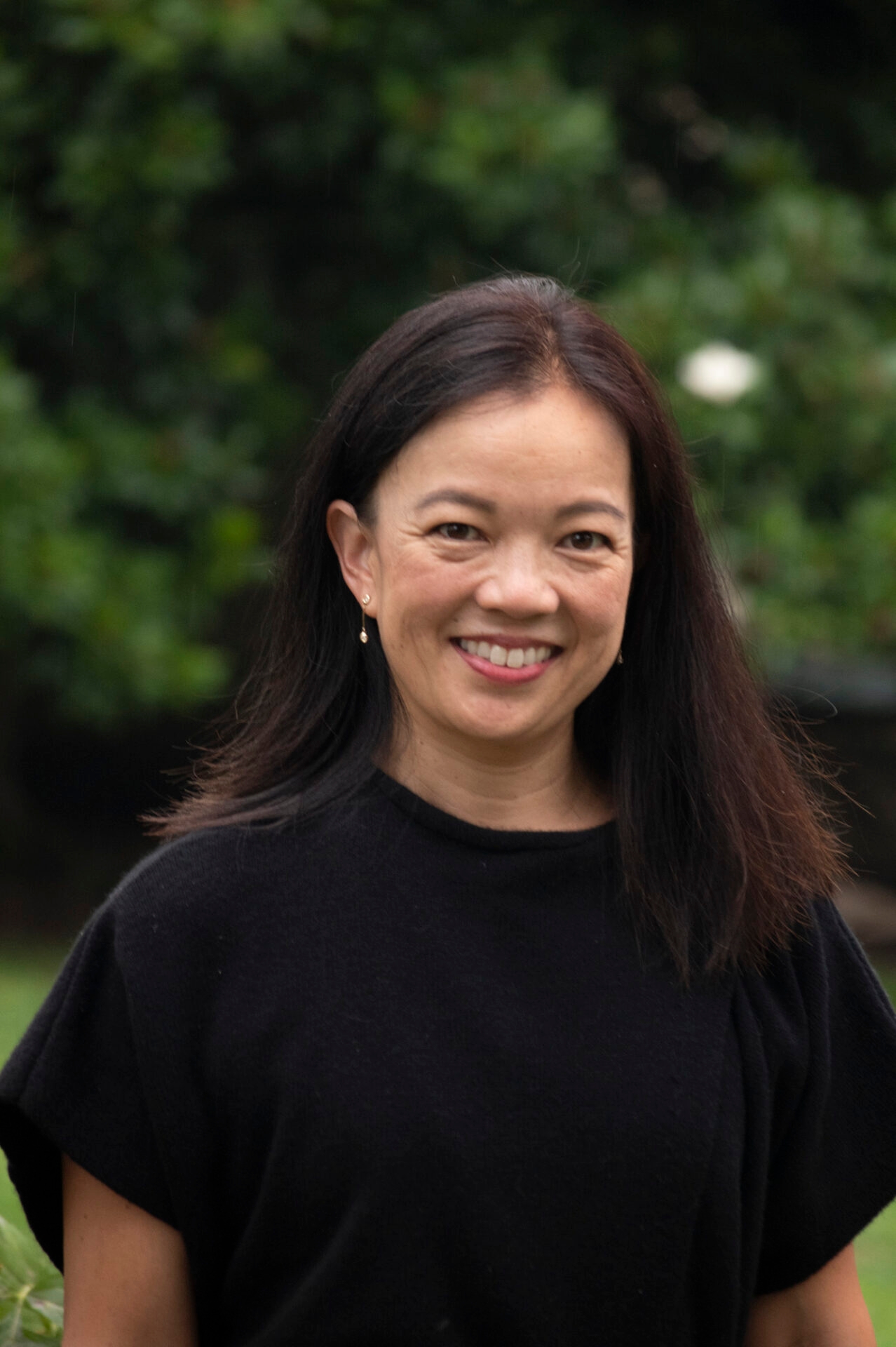 A woman with long brown hair wearing a black shirt smiles at the camera.