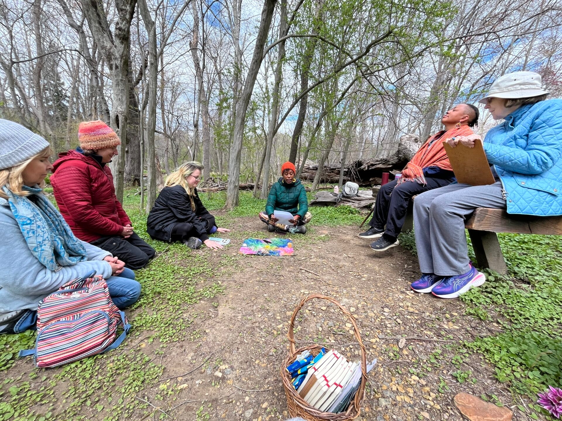 A group of people in hats and coats sit in a circle outdoors